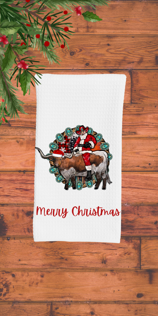 Decorative towel with Santa and reindeer design on a wooden surface with Christmas decorations.
